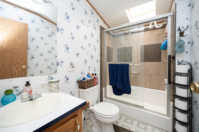 full bathroom featuring a skylight, bath / shower combo with glass door, vanity, a textured ceiling, and toilet