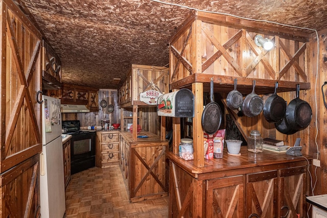 kitchen featuring black electric range, dark parquet floors, white refrigerator, wood walls, and extractor fan