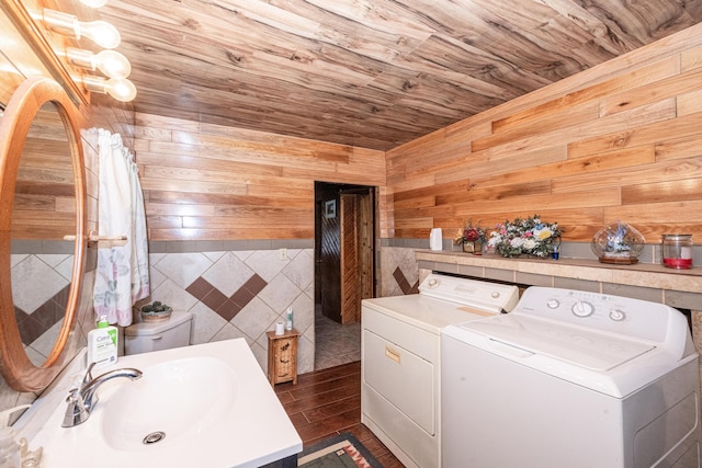 washroom with dark hardwood / wood-style flooring, wood ceiling, wooden walls, sink, and washing machine and clothes dryer