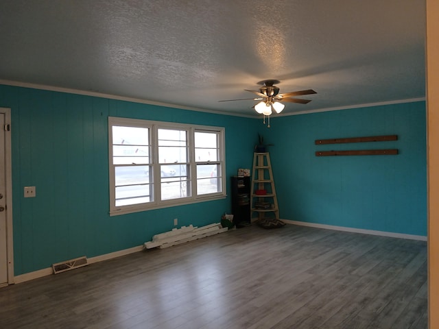 empty room with a textured ceiling, ceiling fan, a baseboard heating unit, crown molding, and hardwood / wood-style flooring