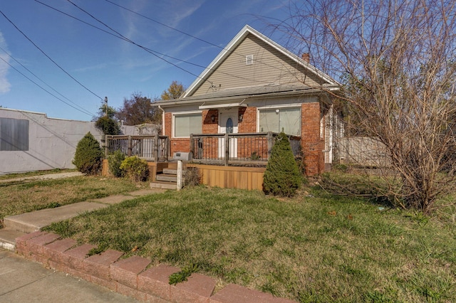 bungalow-style home featuring a front yard and a deck