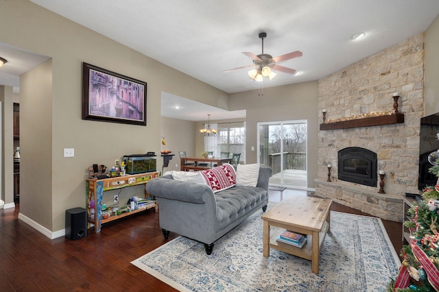 living room featuring a fireplace, dark wood-type flooring, and ceiling fan with notable chandelier