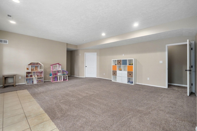 game room with a textured ceiling and light carpet