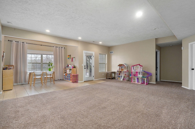 rec room featuring a textured ceiling and light colored carpet