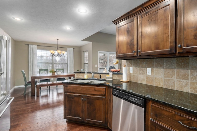 kitchen with dishwasher, a healthy amount of sunlight, dark stone countertops, and sink