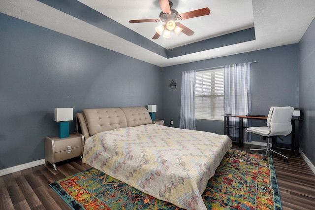 bedroom with a tray ceiling, ceiling fan, and dark hardwood / wood-style floors