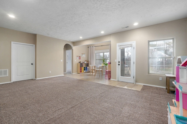 interior space featuring a textured ceiling and light carpet