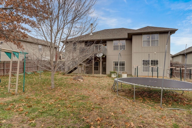 back of house featuring a lawn and a trampoline