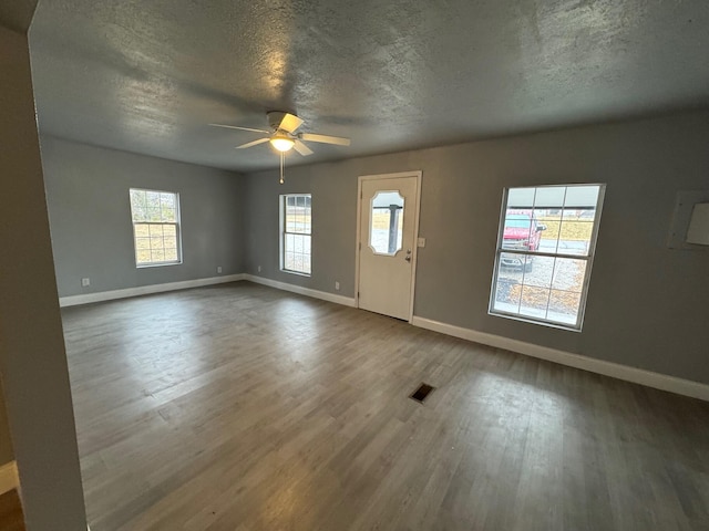 foyer entrance with a textured ceiling, ceiling fan, and dark wood-type flooring