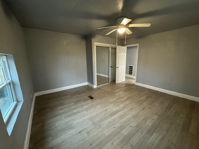 unfurnished bedroom with ceiling fan, wood-type flooring, and a closet