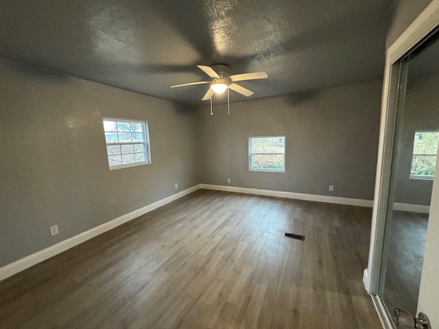 spare room featuring plenty of natural light, ceiling fan, dark hardwood / wood-style flooring, and a textured ceiling