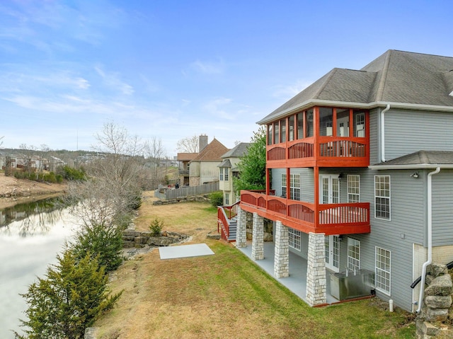 rear view of property with a yard, a water view, and a sunroom