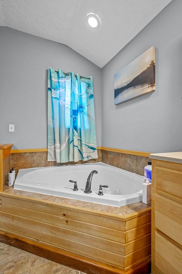 bathroom with vaulted ceiling, tile patterned floors, a washtub, and a textured ceiling