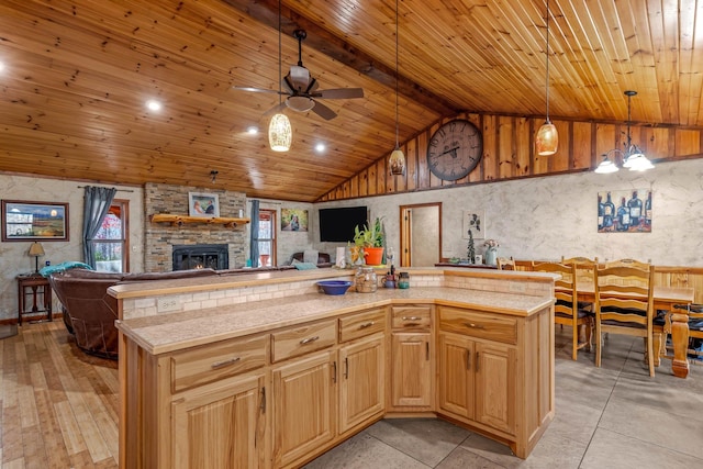 kitchen featuring wood ceiling, ceiling fan, a kitchen island with sink, a fireplace, and hanging light fixtures