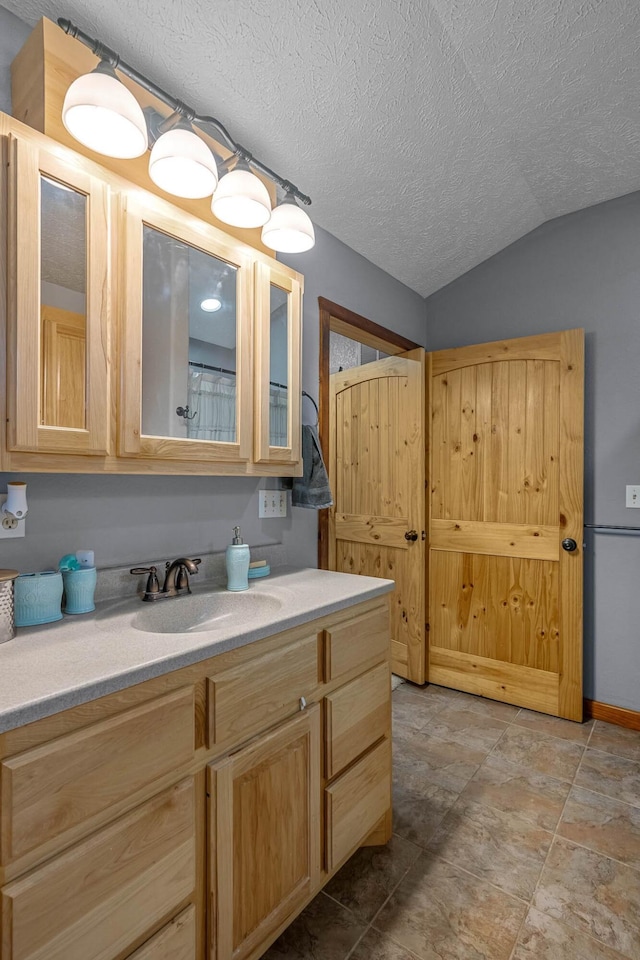 bathroom featuring vanity, a textured ceiling, and vaulted ceiling