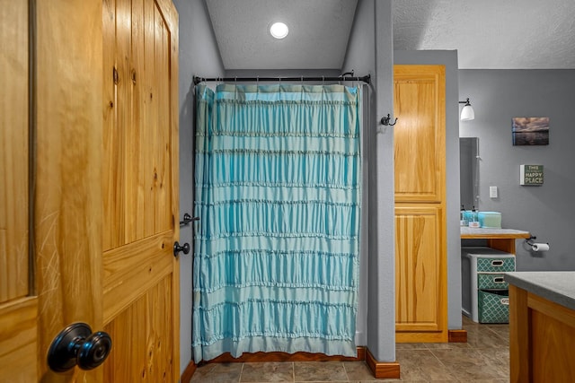 bathroom featuring vanity, a textured ceiling, walk in shower, and tile patterned flooring