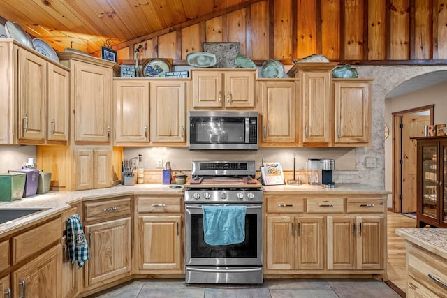 kitchen with light brown cabinets, wooden ceiling, light tile patterned floors, stainless steel appliances, and beverage cooler