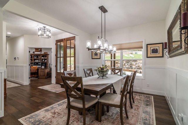 dining space featuring dark wood-type flooring and an inviting chandelier