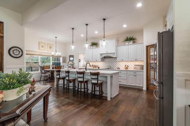 kitchen featuring white cabinetry, stainless steel appliances, dark hardwood / wood-style flooring, an island with sink, and pendant lighting