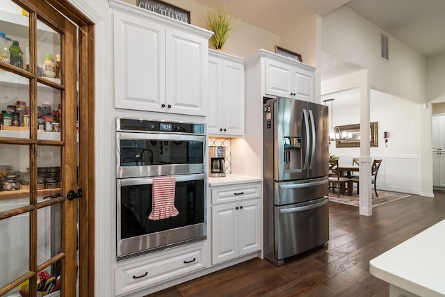 kitchen with appliances with stainless steel finishes, dark hardwood / wood-style flooring, tasteful backsplash, a notable chandelier, and white cabinets