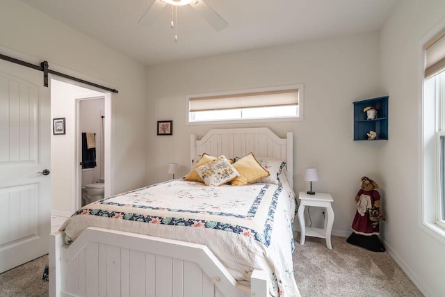 carpeted bedroom with connected bathroom, ceiling fan, and a barn door