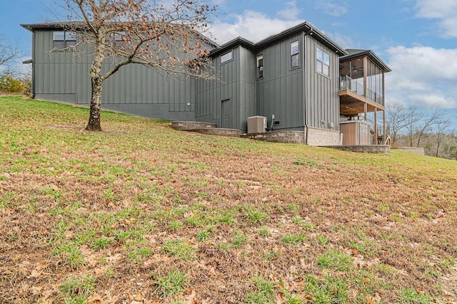 view of home's exterior featuring a lawn, a sunroom, and central AC unit