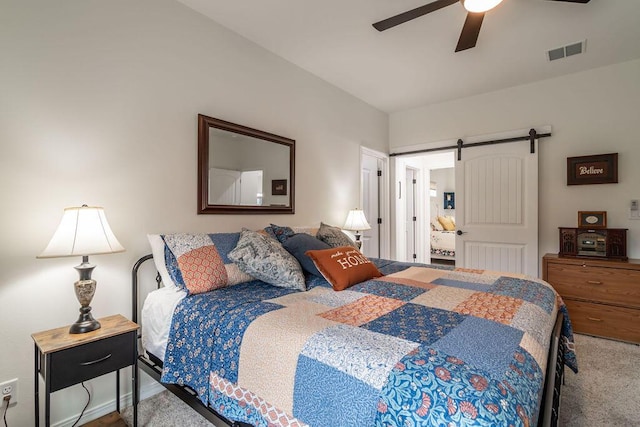 carpeted bedroom featuring a barn door and ceiling fan