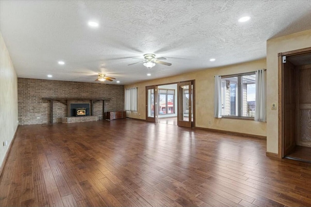 unfurnished living room featuring a textured ceiling, a fireplace, and dark wood-type flooring