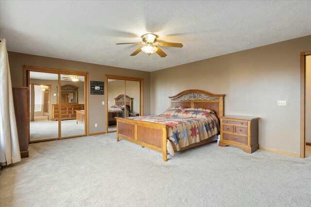 bedroom with carpet flooring, ceiling fan, a textured ceiling, and two closets