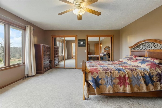 bedroom featuring carpet flooring, ceiling fan, two closets, and multiple windows