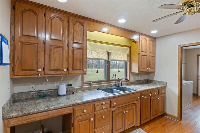 kitchen with a textured ceiling, ceiling fan, light wood-type flooring, and sink