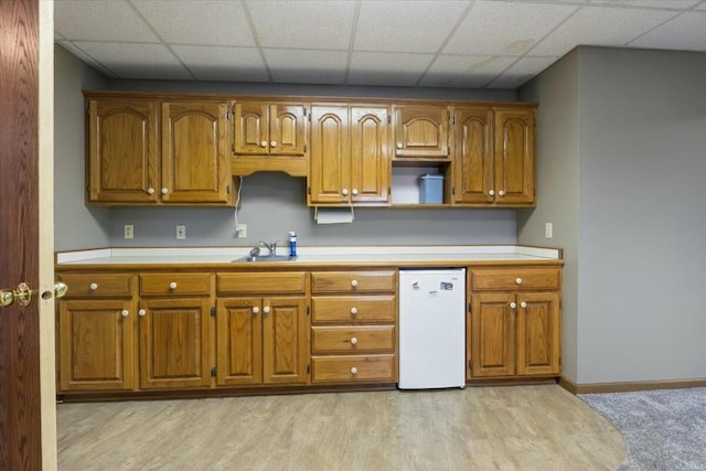 kitchen with dishwasher, light wood-type flooring, a paneled ceiling, and sink