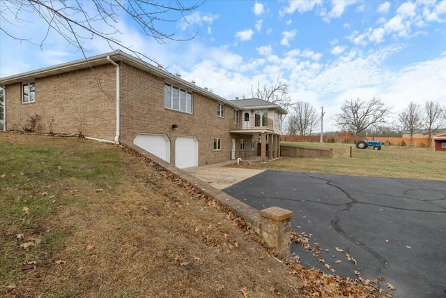 back of house featuring a balcony, a garage, and a lawn