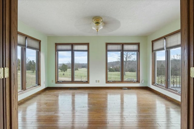 unfurnished sunroom featuring a wealth of natural light and ceiling fan