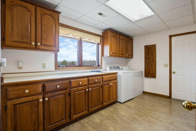 laundry area with cabinets, independent washer and dryer, light wood-type flooring, and sink