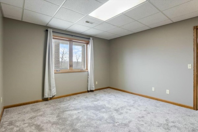 carpeted spare room featuring a drop ceiling