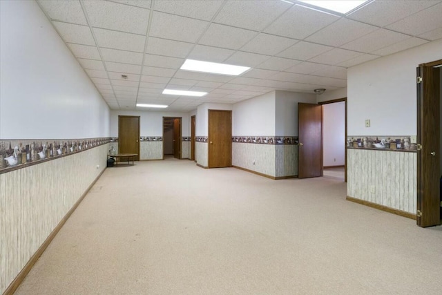 carpeted empty room featuring a drop ceiling