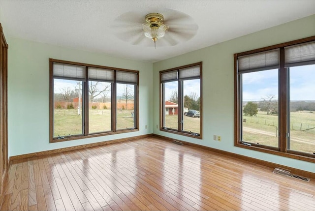 unfurnished sunroom with ceiling fan and plenty of natural light