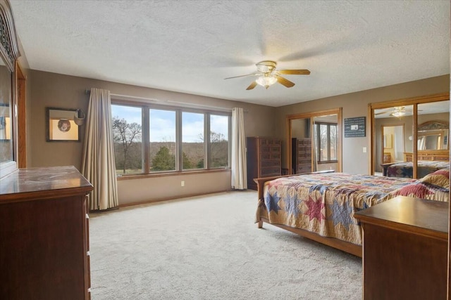 bedroom with ceiling fan, light colored carpet, and a textured ceiling