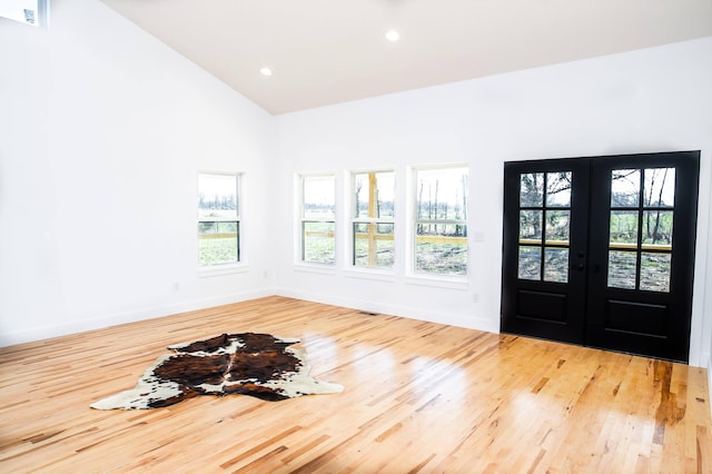 foyer with light hardwood / wood-style flooring, high vaulted ceiling, and french doors