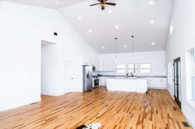 kitchen with white cabinets, appliances with stainless steel finishes, light hardwood / wood-style floors, and high vaulted ceiling