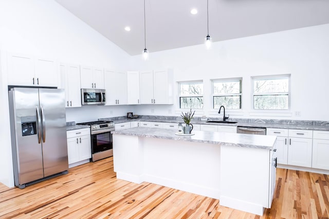 kitchen with sink, stainless steel appliances, light hardwood / wood-style flooring, pendant lighting, and white cabinets