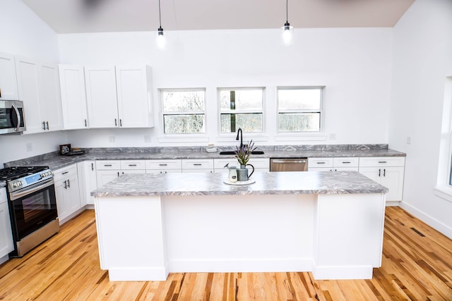 kitchen with pendant lighting, stainless steel appliances, and light wood-type flooring