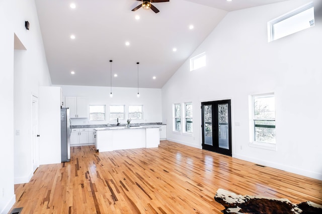 kitchen featuring white cabinets, light hardwood / wood-style flooring, high vaulted ceiling, and plenty of natural light