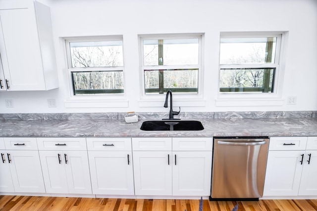 kitchen with light hardwood / wood-style flooring, white cabinets, stainless steel dishwasher, and sink