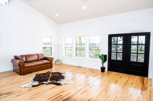 interior space with light hardwood / wood-style floors, high vaulted ceiling, and french doors