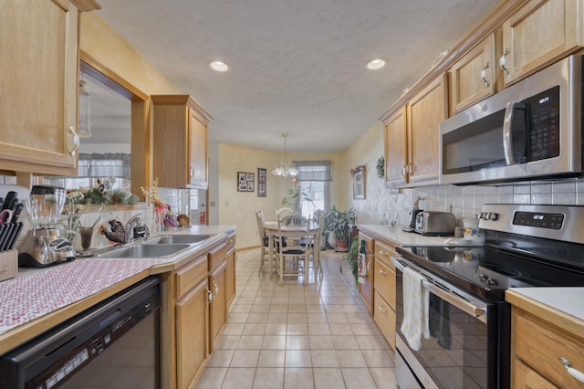 kitchen featuring stainless steel appliances, sink, decorative light fixtures, a chandelier, and light tile patterned flooring