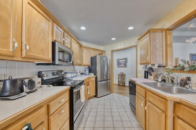 kitchen with decorative backsplash, sink, light tile patterned floors, and stainless steel appliances