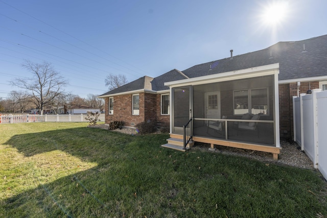 rear view of property featuring a sunroom and a yard