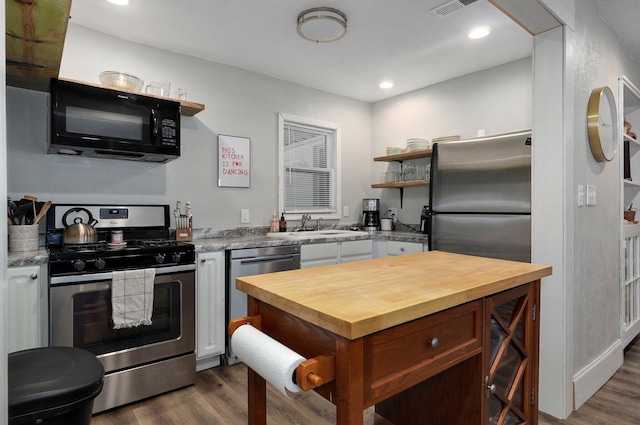 kitchen with sink, light stone counters, dark hardwood / wood-style flooring, and stainless steel appliances